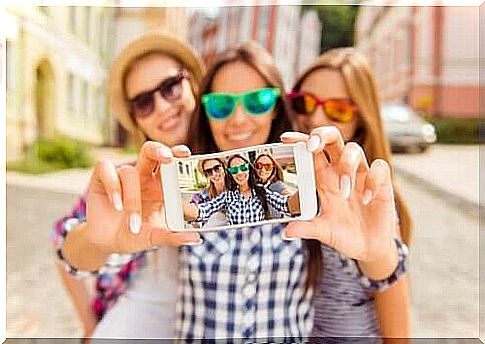 Three smiling girlfriends with sunglasses take a selfie 