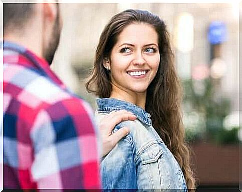 Young woman smiles at a man who puts his hand on her shoulder