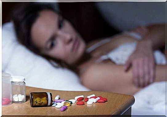 A woman is looking at medication at the bedside table