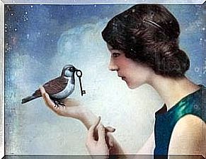 A woman holds a bird with a key in her mouth