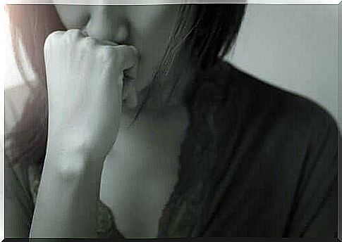 A woman with her hand in front of her mouth due to worry.