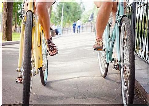 We see the legs of two friends riding side by side on their bikes