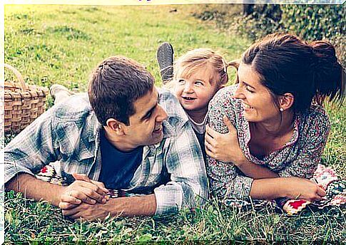 Smiling parents with their little daughter in the park.