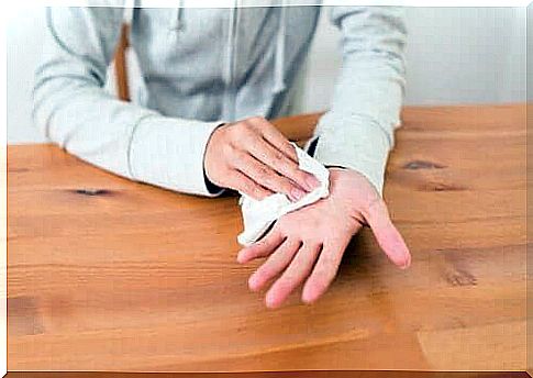 A person wiping his sweaty hand with a napkin.