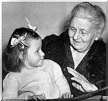 Maria Montessori talks to a little girl.