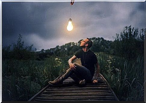 A guy looks at a light bulb at night