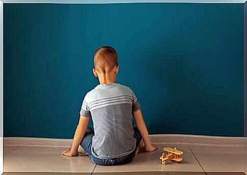 A child sitting in front of a wall with a toy plane.