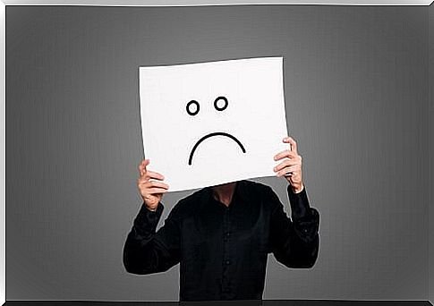 A man holds up a sign with a negative face