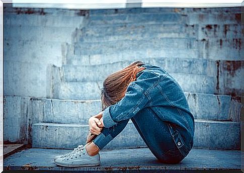 A sad teenager with his head on his knees.