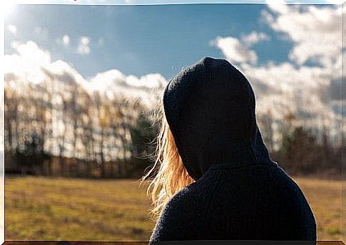 A teenage girl with teenage anxiety looks at the forest.