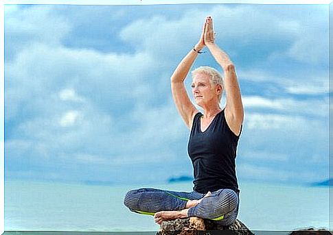 Midorexia - an elderly woman sitting on a rock and doing yoga.