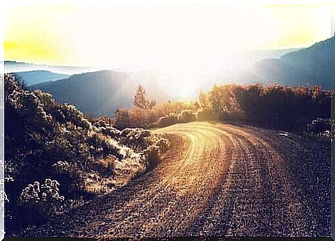 The sun shining over the mountain on a road